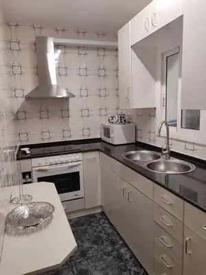 a kitchen with white cabinets and a sink and a microwave at Apartamento Bella Carmen : para 6 personas in Cunit