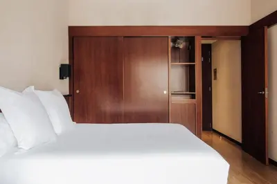 a bedroom with a white bed and a wooden cabinet at Hotel Derby in Barcelona