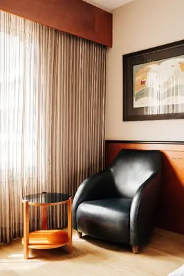 a black leather chair in a room with a window at Hotel Derby in Barcelona