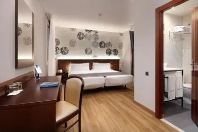 a hotel room with a bed and a desk and a bedroom at HCC Taber in Barcelona