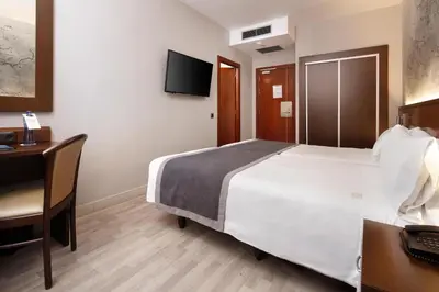 a hotel room with a large bed and a desk at HCC Taber in Barcelona