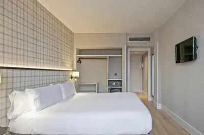 a bedroom with a white bed and a television at Acta CITY47 in Barcelona