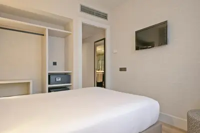 a bedroom with a white bed and a flat screen tv at Acta CITY47 in Barcelona