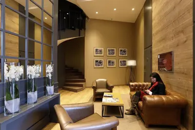 a woman sitting on a leather chair in a waiting room at Guitart Grand Passage in Barcelona