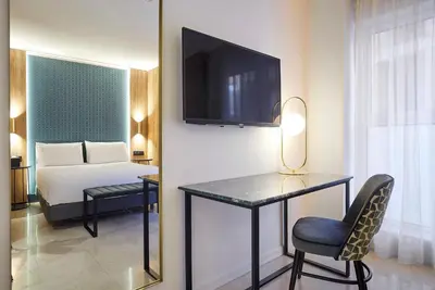 a room with a bed and a desk with a television at Exe Mitre in Barcelona