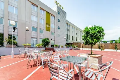 an outdoor patio with tables and chairs in front of a building at Exe Parc del Vallés in Cerdanyola del Valles