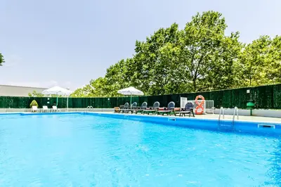 a large swimming pool with chairs and umbrellas at Exe Parc del Vallés in Cerdanyola del Valles