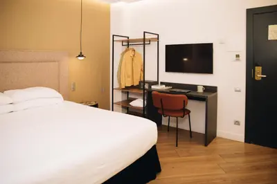 a bedroom with a bed and a desk with a television at H La Paloma Boutique in Barcelona