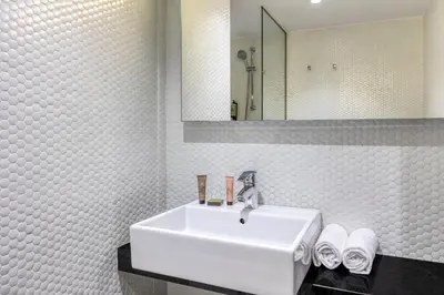 a white bathroom with a sink and a mirror at Citadines Ramblas Barcelona in Barcelona