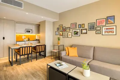 a living room with a couch and a kitchen at Citadines Ramblas Barcelona in Barcelona