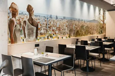 a restaurant with tables and chairs and a large mural at Hotel Travessera in Barcelona