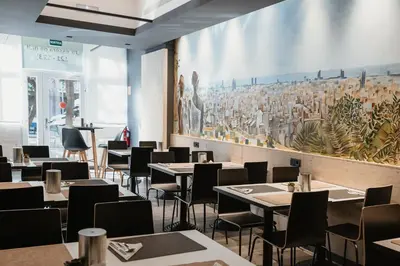 a restaurant with tables and chairs and a painting on the wall at Hotel Travessera in Barcelona