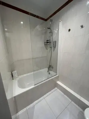 a white bathroom with a shower and a tub at Hotel Travessera in Barcelona