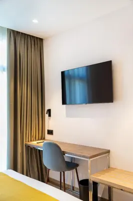 a room with a desk and a television on the wall at Caledonian in Barcelona