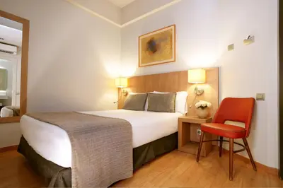 a hotel room with a bed and a red chair at Arc La Rambla in Barcelona