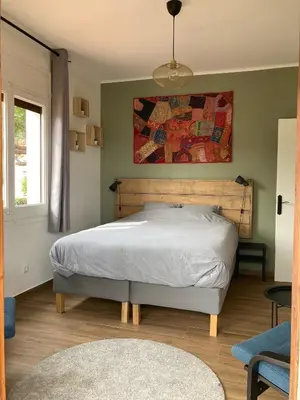 a bedroom with a bed and a painting on the wall at Cozy place, big roof terrace & spectacular views. in Cabrils