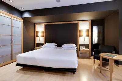 a hotel room with a large bed and a chair at Hotel Barcelona Universal in Barcelona