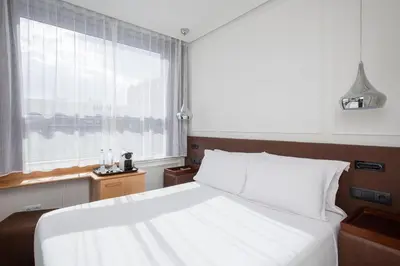 a bedroom with a large white bed and a window at H10 Itaca in Barcelona