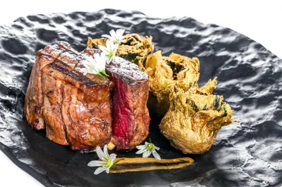 a black plate with steak and other foods on it at Eurostars Grand Marina Hotel GL in Barcelona