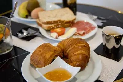a plate of food with croissants and a cup of soup at Elite Hotel - Gay Men Only in Sitges
