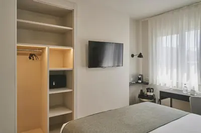 a bedroom with a bed and a television on a wall at Tres Torres Atiram Hotel in Barcelona