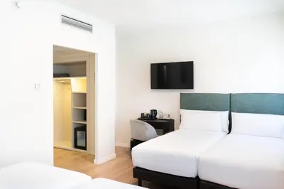 a bedroom with a bed and a tv on the wall at Tres Torres Atiram Hotel in Barcelona