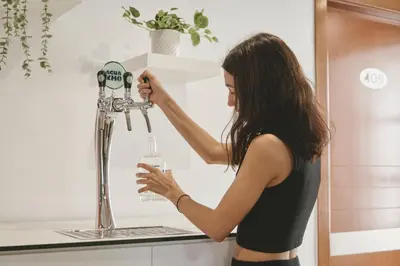 a woman holding a bottle of water in a machine at Tres Torres Atiram Hotel in Barcelona