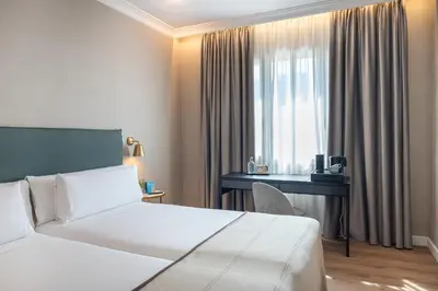 a hotel room with two beds and a desk at Tres Torres Atiram Hotel in Barcelona