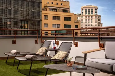 a patio with chairs and tables on a balcony at NH Collection Barcelona Gran Hotel Calderon in Barcelona
