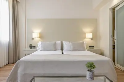 a hotel room with a large bed and a chair at Aparthotel Mariano Cubi Barcelona in Barcelona