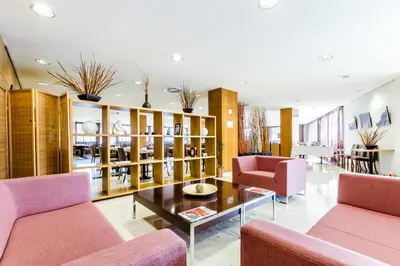 a living room with pink chairs and a coffee table at Exe Barbera Parc in Barbera del Valles