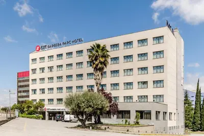 a white building with a palm tree in front of it at Exe Barbera Parc in Barbera del Valles
