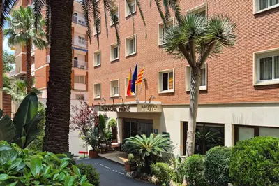 a building with a flag and palm trees in front of it at Bonanova Park in Barcelona