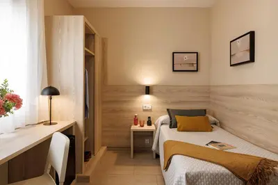 a small bedroom with a bed and a desk at Bonanova Park in Barcelona