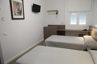 a small room with two beds and a tv at Hotel Alguer Camp Nou in Barcelona