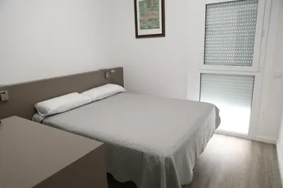 a white room with two beds and a window at Hotel Alguer Camp Nou in Barcelona