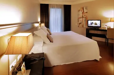 a hotel room with a white bed and a television at Hotel Condado in Barcelona