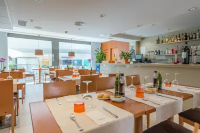 a restaurant with tables and chairs and a bar at Atenea Park Suites & Apartments in Vilanova i la Geltrú