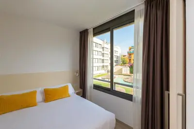 a bedroom with a bed and a large window at Atenea Park Suites & Apartments in Vilanova i la Geltrú