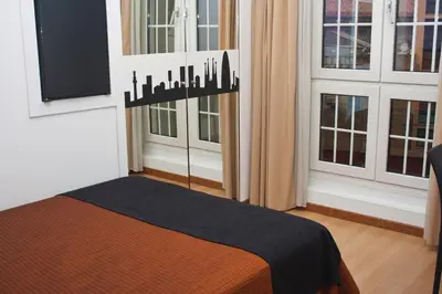 a bedroom with a bed and two windows at Hotel Abbot in Barcelona