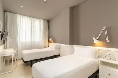 a hotel room with two beds and a desk at Paral·lel in Barcelona