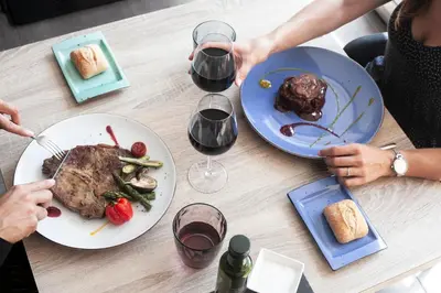 a table with two plates of food and two glasses of wine at Ibersol Antemare - Adults Only in Sitges