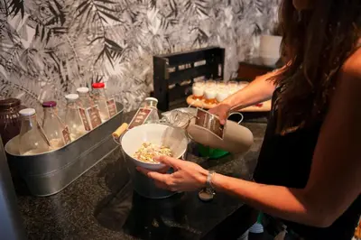 a woman is preparing food in a bowl on a counter at Ibersol Antemare - Adults Only in Sitges