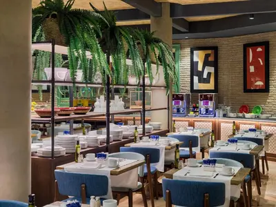 a restaurant with white tables and blue chairs at H10 Marina Barcelona in Barcelona