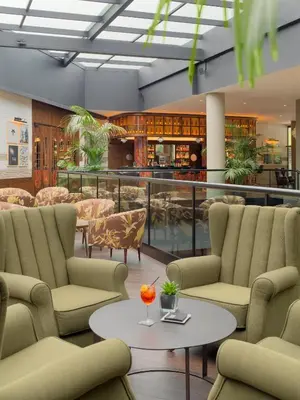 a lobby with chairs and a table and a bar at H10 Marina Barcelona in Barcelona