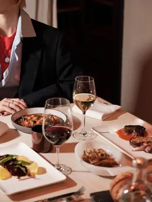 a woman sitting at a table with plates of food and wine at Hotel Neri – Relais & Chateaux in Barcelona