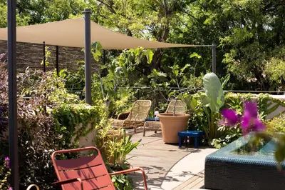 a patio with chairs and plants and an umbrella at Hotel Neri – Relais & Chateaux in Barcelona