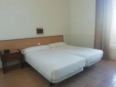 a bedroom with a bed with white sheets and a night stand at Hotel Monegal in Barcelona