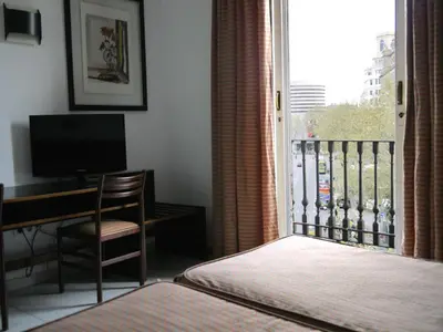 a bedroom with a bed and a desk and a window at Hotel Monegal in Barcelona