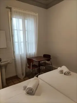 a room with two beds and a desk and a window at Hotel Monegal in Barcelona